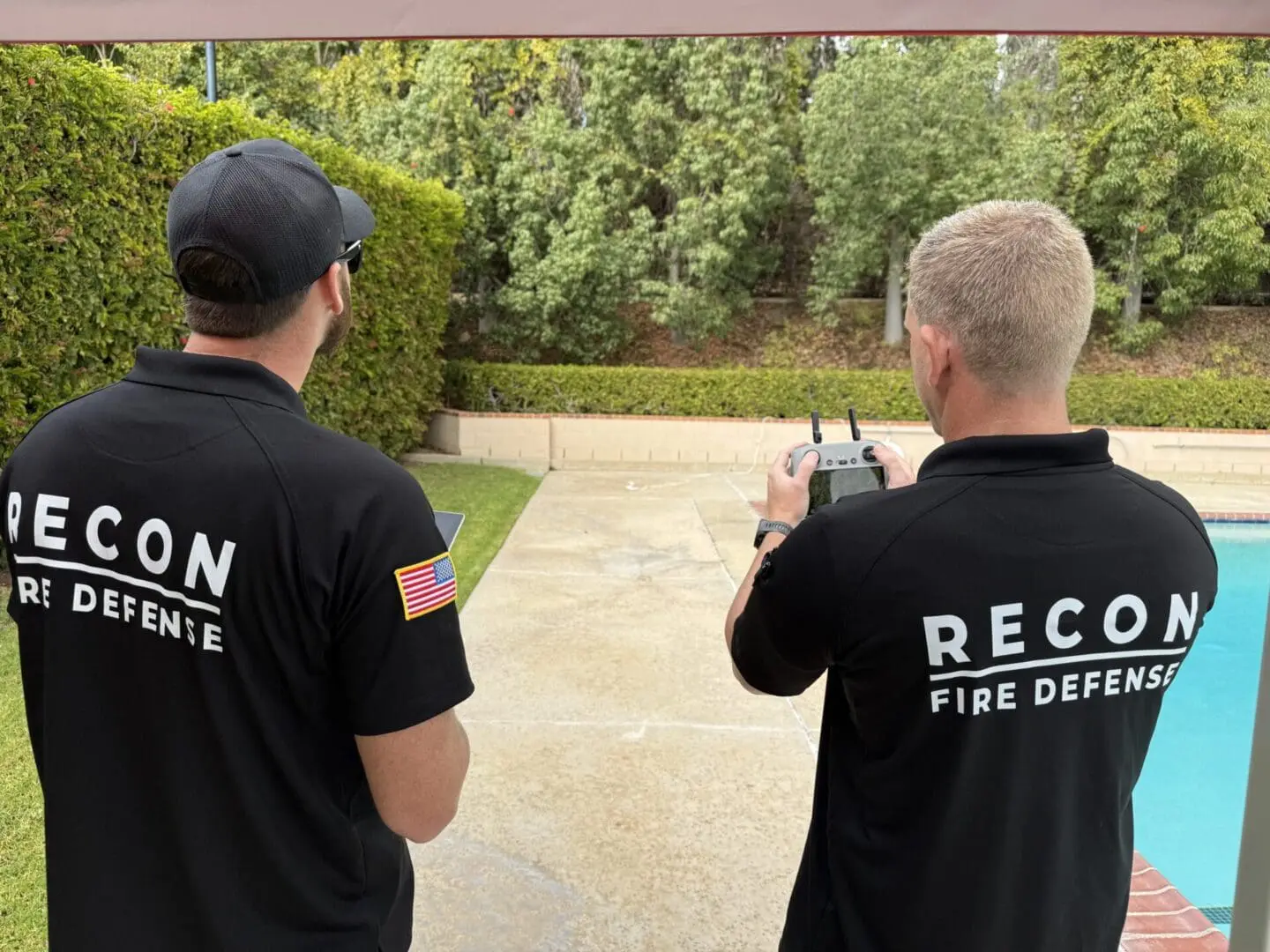 Two men operating a drone near pool.